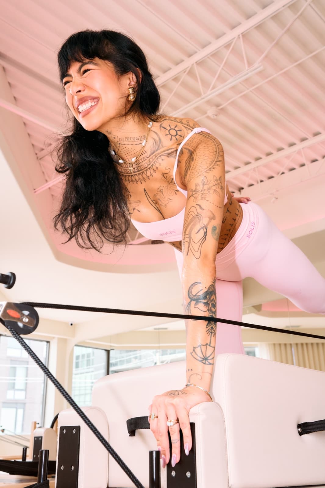 Instructor laughing on the reformer in pink Solis activewear