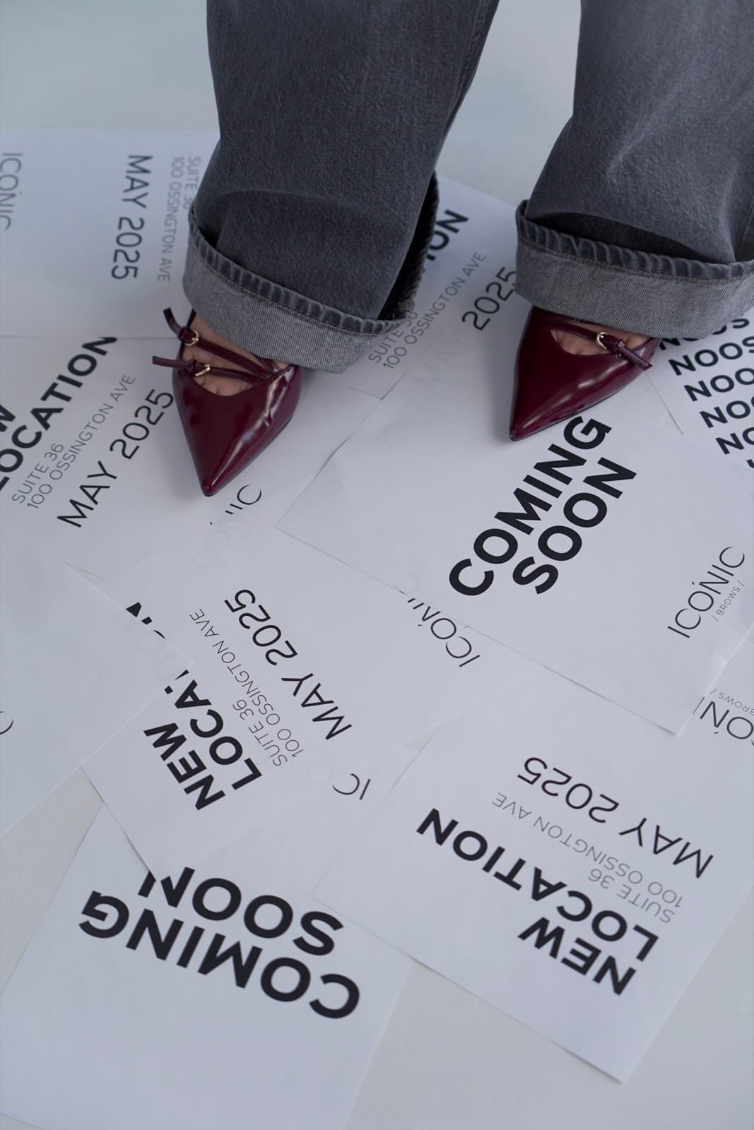 Burgundy heels and cuffed grey jeans on New Location and Coming Soon posters